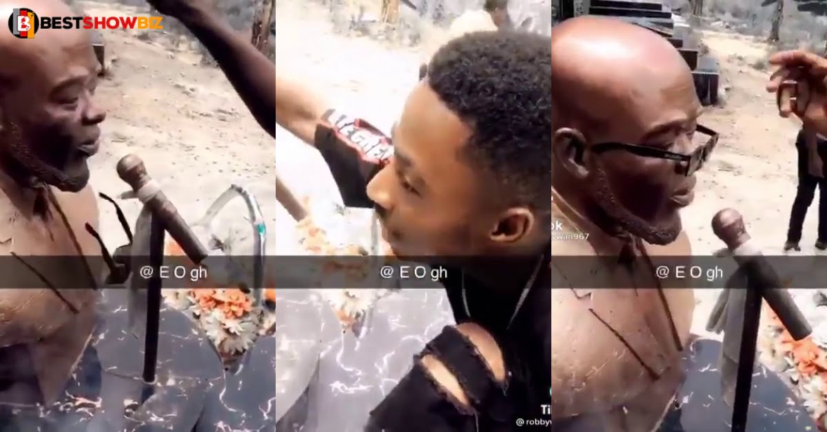 Young man disrespects the memory of Kofi B, as he storms his grave to slap his statue (video)